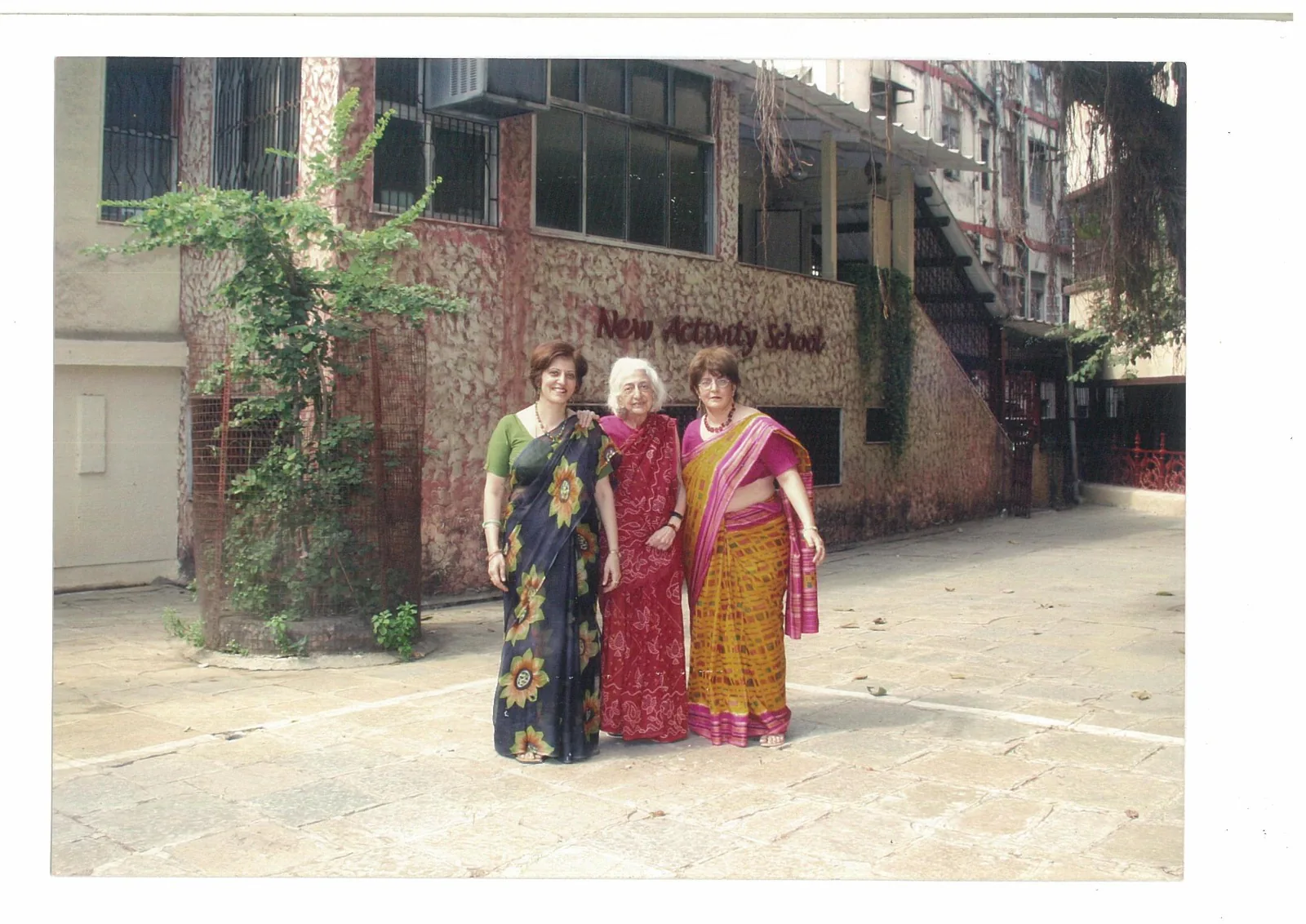 Three women standing together in the New Activity School courtyard