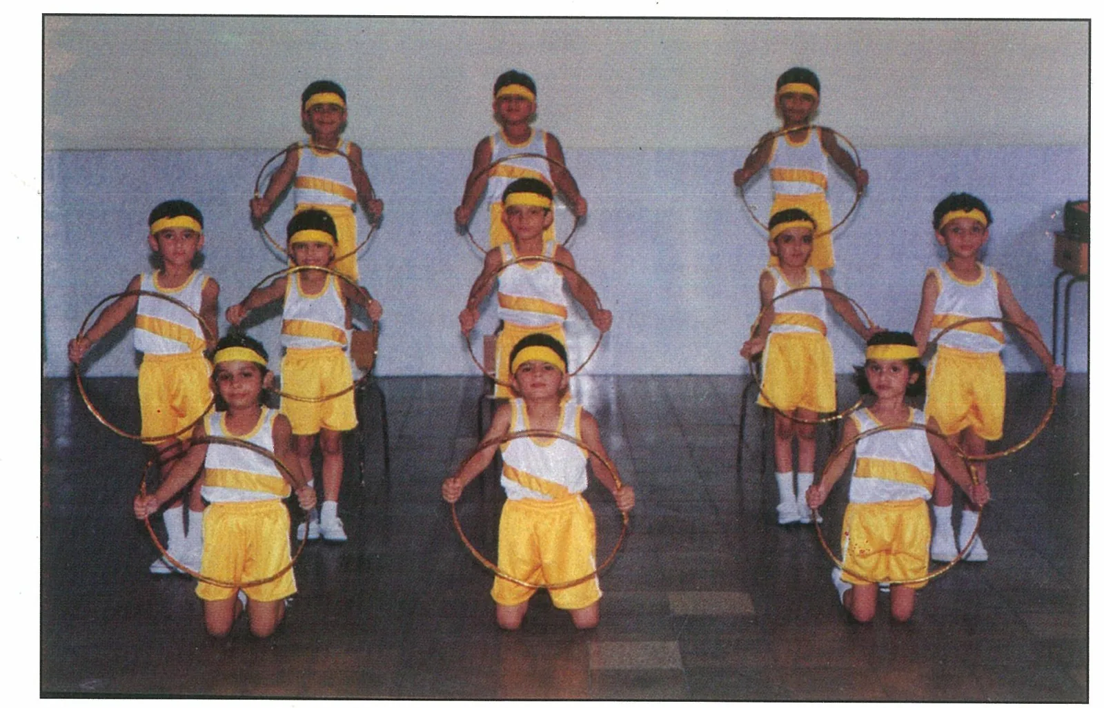 Children in yellow costumes holding hoops for a performance